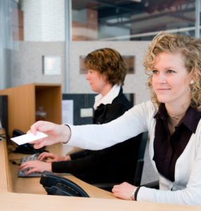 receptionists sitting at their desk returning an insurance card to their client