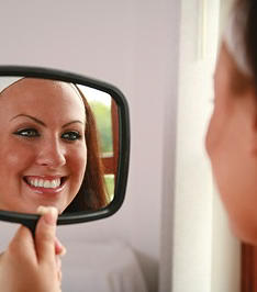 woman looking in mirror after dental cleaning