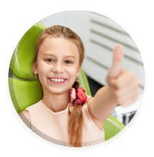 little girl dental patient giving a thumbs up in a dental exam chair