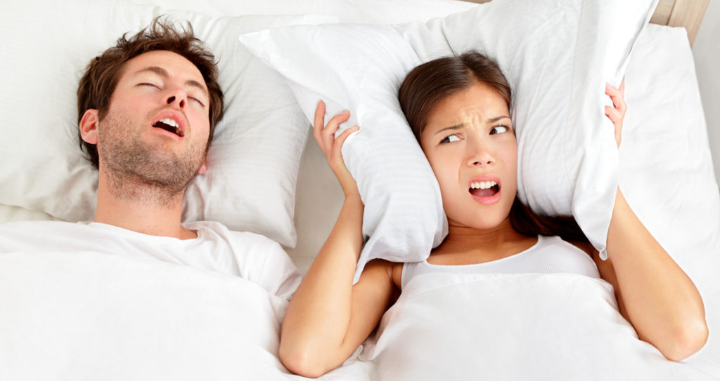 woman frustrated over a man snoring in bed